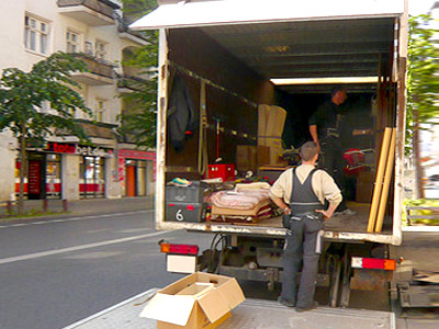 Ein Umzugswagen mit Möbeln und Umzugshelfern auf der Straße.